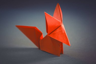 Turuncu kağıt tilki origamisi boş gri bir arkaplanda izole edildi.