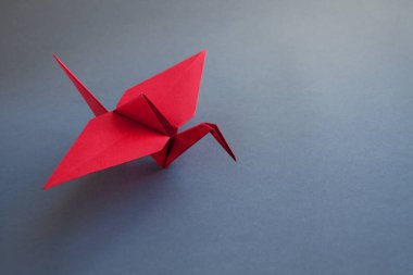 Kırmızı kağıt turna origamisi boş gri bir arkaplanda izole edildi.