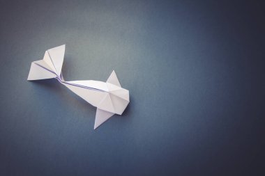 Beyaz kağıt balığının origamisi gri bir arkaplanda izole edilmiş.