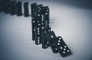 Arka planda siyah domino taşları zinciri. Domino etkisi kavramı