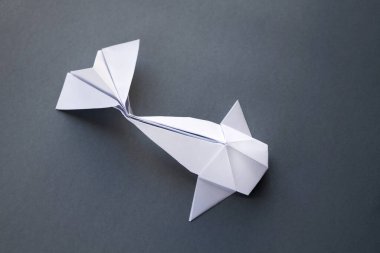 Beyaz kağıt balığının origamisi gri bir arkaplanda izole edilmiş.