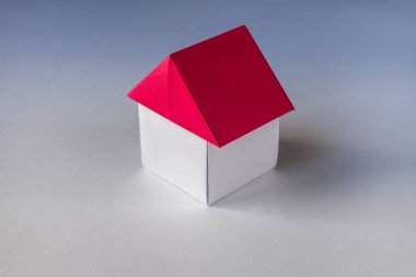 Beyaz ve kırmızı kağıt ev origamisi boş bir arkaplanda izole edildi.