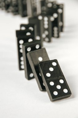 Beyaz arka planda siyah domino taşları zinciri. Domino etkisi kavramı