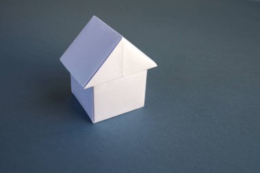 Beyaz kağıt ev origamisi boş gri bir arkaplanda izole edildi.