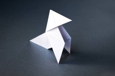 Beyaz kağıttan tavuk origamisi gri bir arkaplanda izole edilmiş. Cocotte en paper
