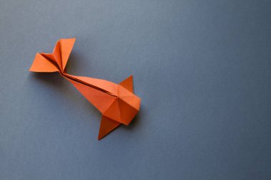 Turuncu kağıttan balık origamisi boş gri bir arkaplanda izole edilmiş.