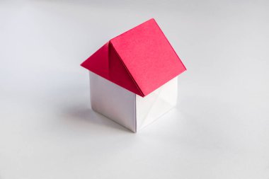 Beyaz ve kırmızı kağıt ev origamisi boş bir arkaplanda izole edildi.