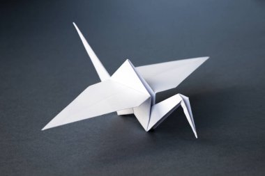 Beyaz kağıt turna origamisi boş gri bir arkaplanda izole edildi.