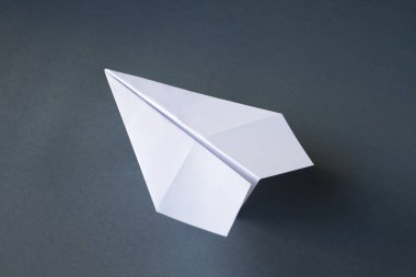 Beyaz kağıt uçak origamisi boş gri bir arkaplanda izole edildi