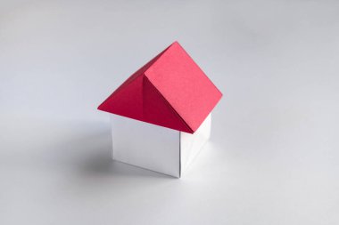 Beyaz ve kırmızı kağıt ev origamisi boş bir arkaplanda izole edildi.