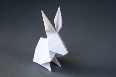Beyaz kağıttan tavşan origamisi boş gri bir arkaplanda izole edilmiş..