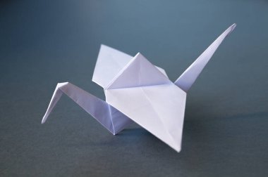 Beyaz kağıt turna origamisi boş gri bir arkaplanda izole edildi.