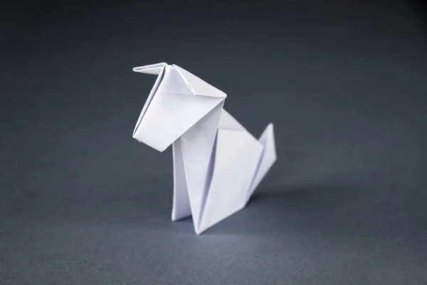 White paper dog origami isolated on a blank grey background.