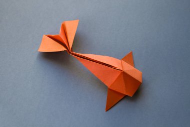 Turuncu kağıttan balık origamisi boş gri bir arkaplanda izole edilmiş.