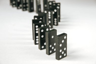 Beyaz arka planda siyah domino taşları zinciri. Domino etkisi kavramı