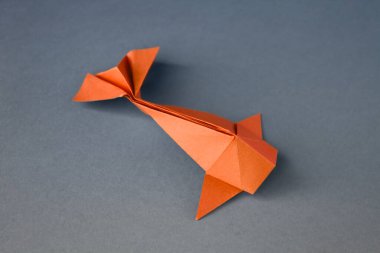 Turuncu kağıttan balık origamisi boş gri bir arkaplanda izole edilmiş.