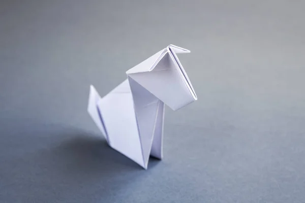 White paper dog origami isolated on a blank grey background.