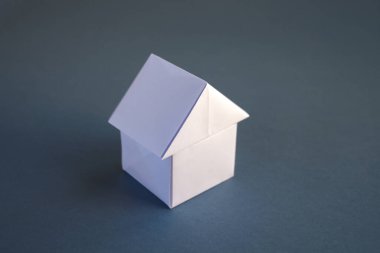 Beyaz kağıt ev origamisi boş gri bir arkaplanda izole edildi.