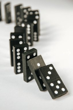 Beyaz arka planda siyah domino taşları zinciri. Domino etkisi kavramı
