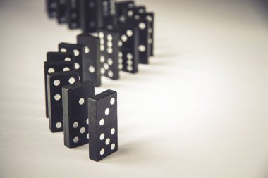 Beyaz arka planda siyah domino taşları zinciri. Domino etkisi kavramı