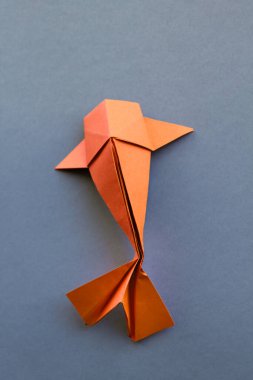Turuncu kağıttan balık origamisi boş gri bir arkaplanda izole edilmiş.