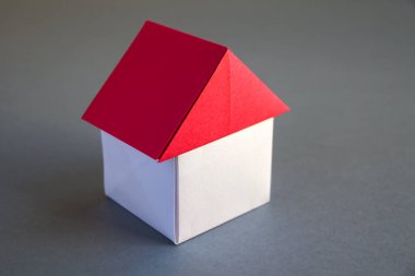 White and red paper house origami isolated on a grey background.