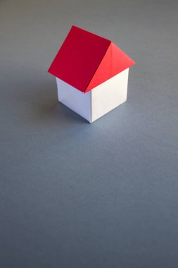 White and red paper house origami isolated on a grey background.