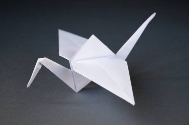 Beyaz kağıt turna origamisi boş gri bir arkaplanda izole edildi.