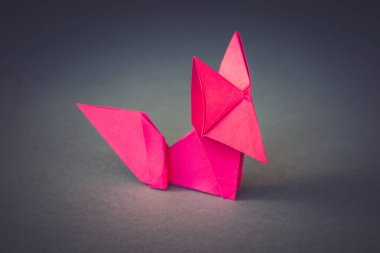 Pembe kağıt tilki origamisi boş gri bir arkaplanda izole edilmiştir..