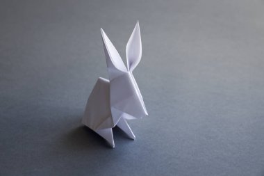 Beyaz kağıttan tavşan origamisi boş gri bir arkaplanda izole edilmiş..