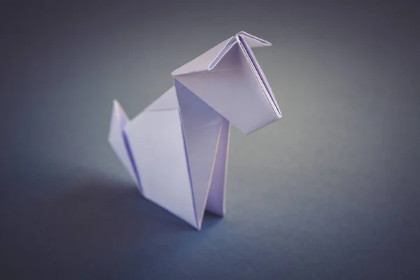 White paper dog origami isolated on a blank grey background.