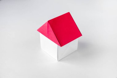 Beyaz ve kırmızı kağıt ev origamisi boş bir arkaplanda izole edildi.