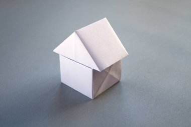 Beyaz kağıt ev origamisi boş gri bir arkaplanda izole edildi.