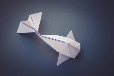 Beyaz kağıt balığının origamisi gri bir arkaplanda izole edilmiş.