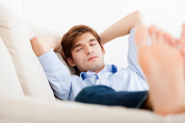 Mies makaa sohvalla — kuvapankkivalokuva
