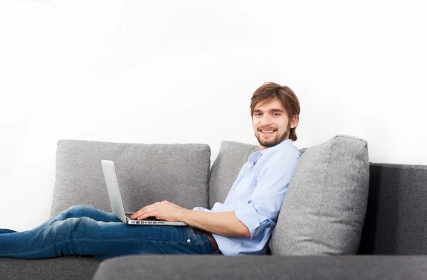 Muž s laptopem ležící doma na pohovce — Stock fotografie