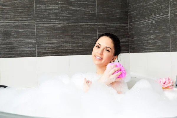 Vackert leende kvinna tvätt axeln med rosa svamp — 图库照片