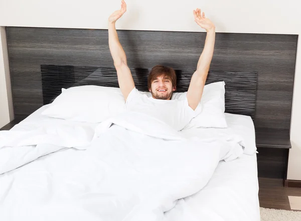 Hombre guapo acostado despertando estirándose y bostezando acostado en la cama — Foto de Stock