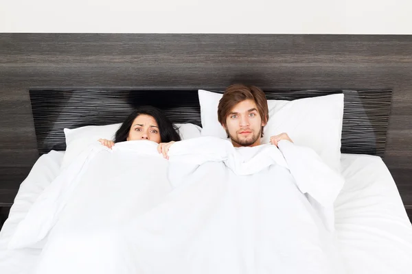 Sorpresa pareja acostada en una cama — Foto de Stock