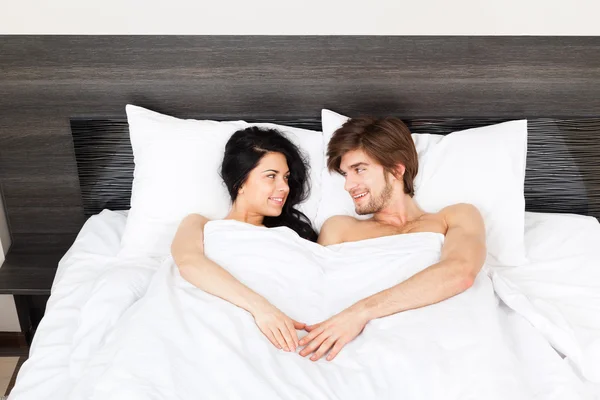 Jeune couple couché dans un lit — Photo