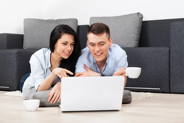 Jeune couple heureux smilling en utilisant un ordinateur portable — Photo