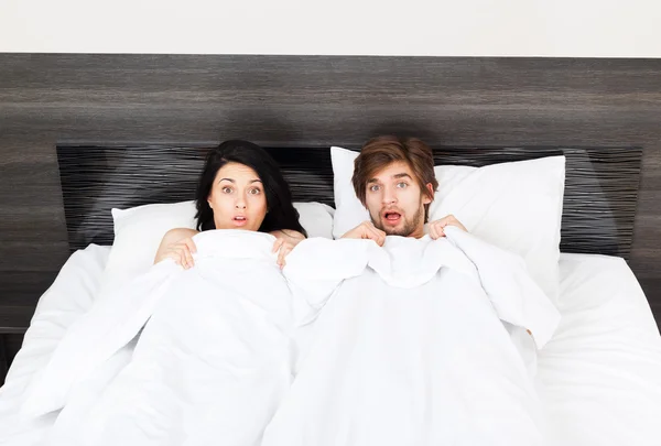 Unhappy surprise couple lying in a bed — Stock Photo, Image