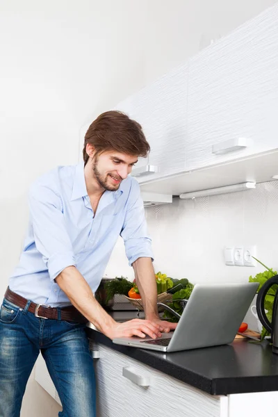 Hombre joven en casa cocina sonrisa feliz usando la cocina portátil —  Fotos de Stock