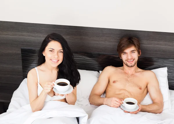 Mladý pár si kávu v posteli — Stock fotografie