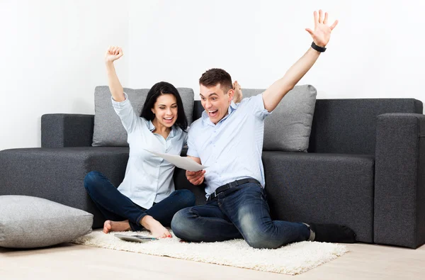 Casal feliz lendo uma carta em sua sala de estar — Fotografia de Stock