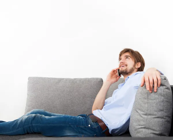 Jonge man liggen ontspannen op de bank praten over telefoon — Stockfoto