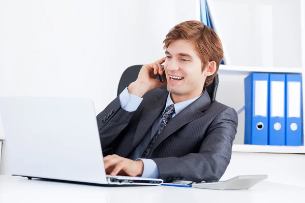 Biznesmen rozmowy na telefon komórkowy za pomocą laptopa — Zdjęcie stockowe
