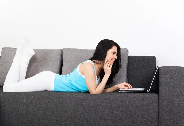 Vrouw met laptop liggend op de Bank — Stockfoto