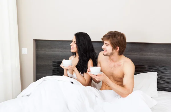 Jovem casal beber café na cama — Fotografia de Stock