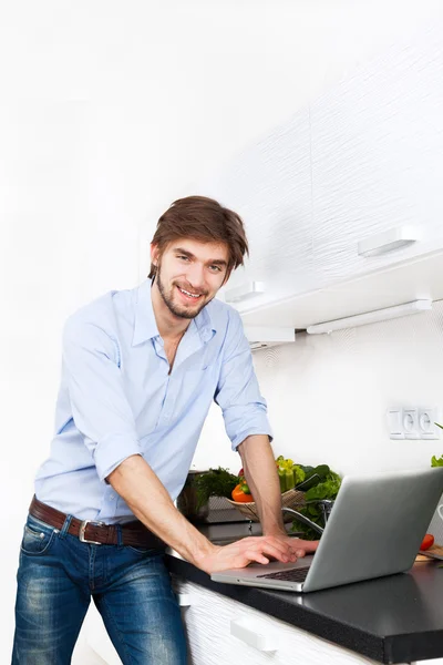 Hombre joven en casa cocina sonrisa feliz usando la cocina portátil —  Fotos de Stock